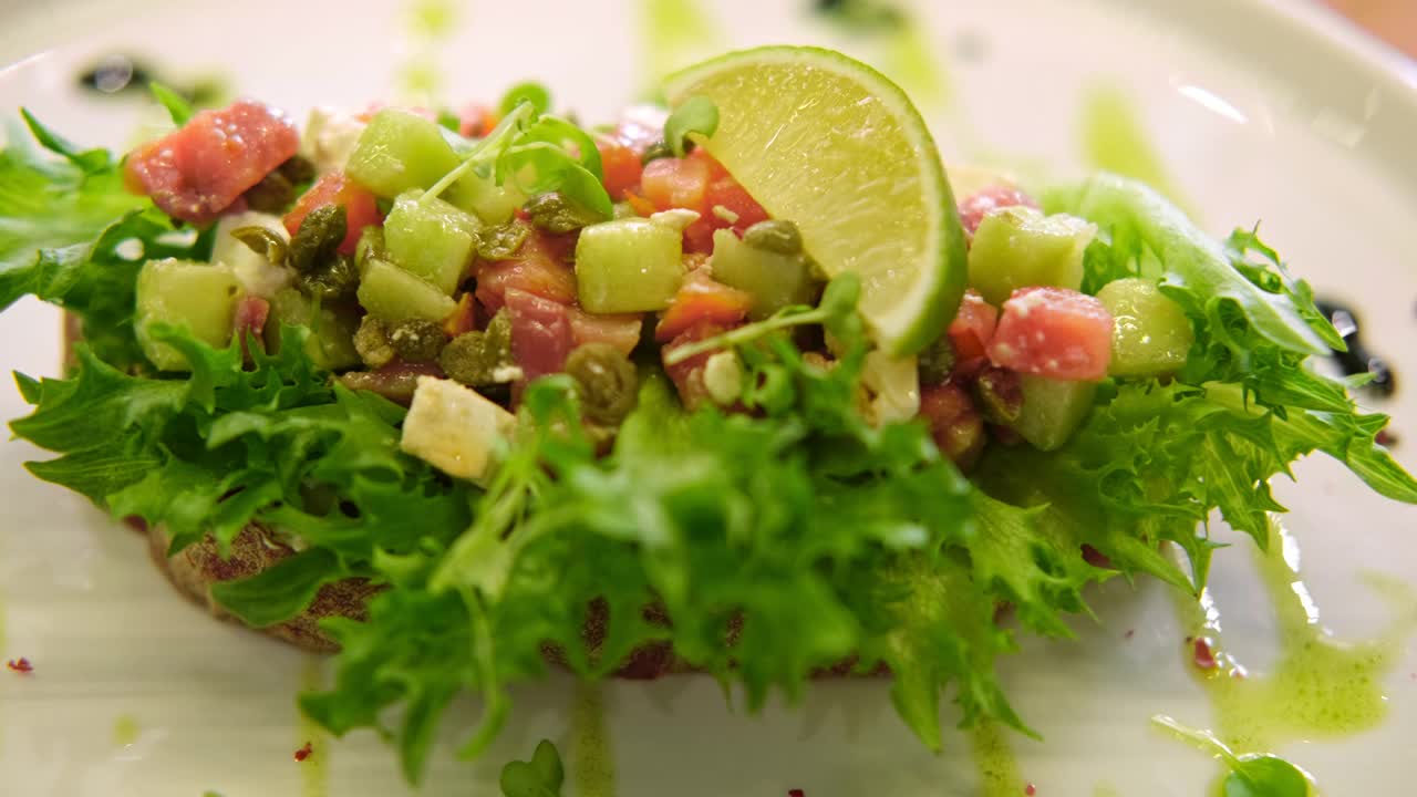 流行的食物背景。白盘子里的意式烤面包配切碎的蔬菜和烟熏鲑鱼。橄榄油和香料装饰。Copyspace。前视图。传统的意大利开胃菜。开胃菜,点心