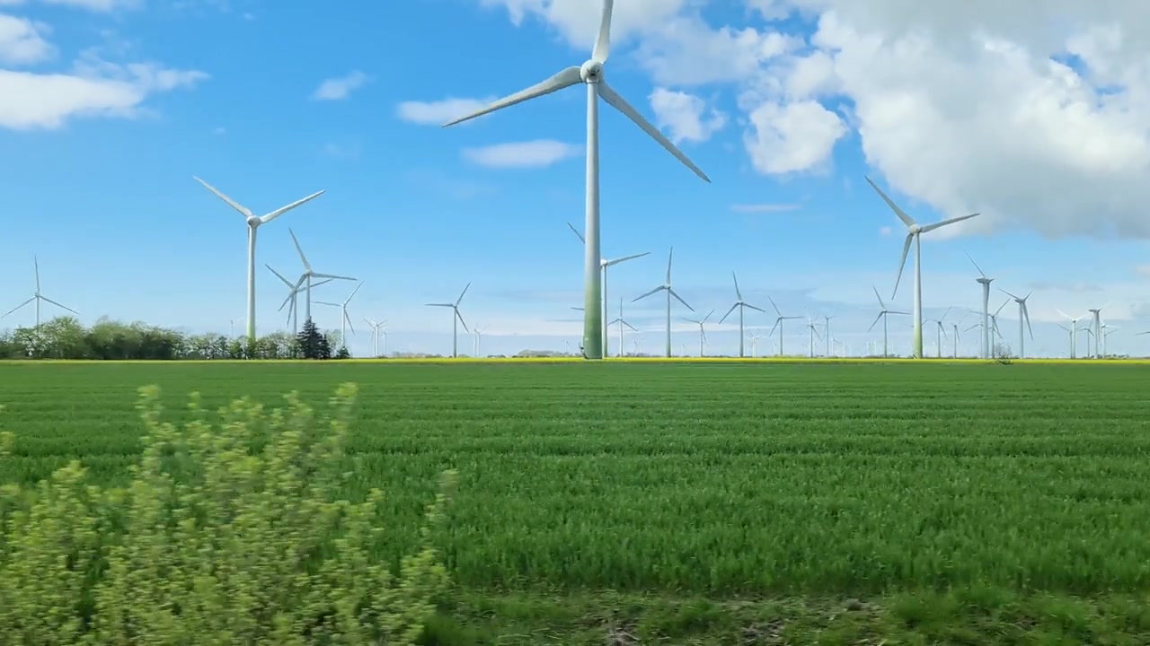 詳情圖-從行駛中的汽車側窗看到草地上的大型風力發(fā)電場。