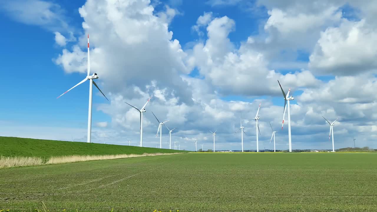 從行駛中的汽車側窗看到草地上的大型風力發(fā)電場。