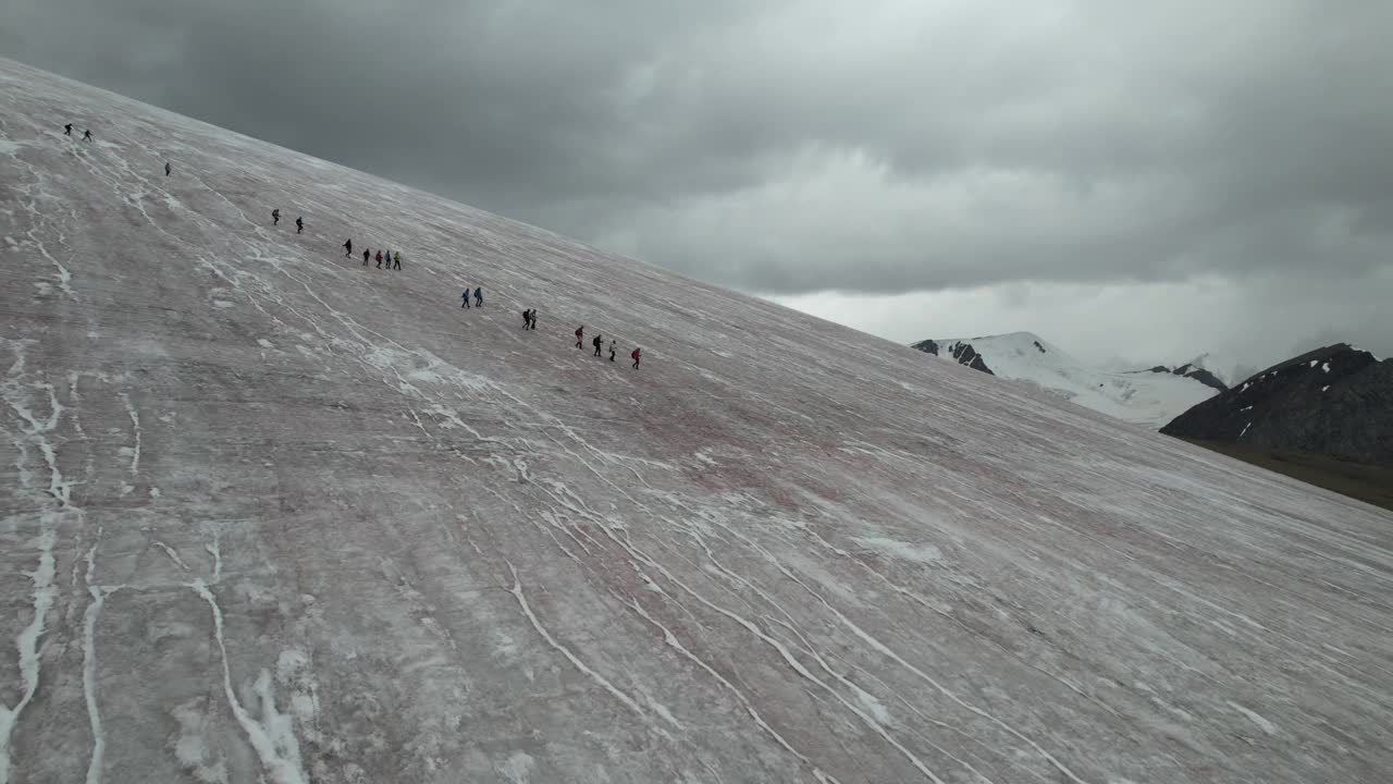 登山者组成一队从冰川上下来。无人机拍摄的视频。