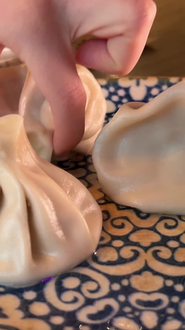 用手把螳螂放在盘子里。妇女拿着传统的格鲁吉亚饺子，Khinkali，用叉子，近距离观察双手。