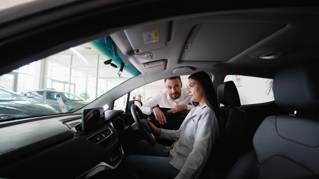 汽车销售商帮助一位女性客户选择新车。右舵车