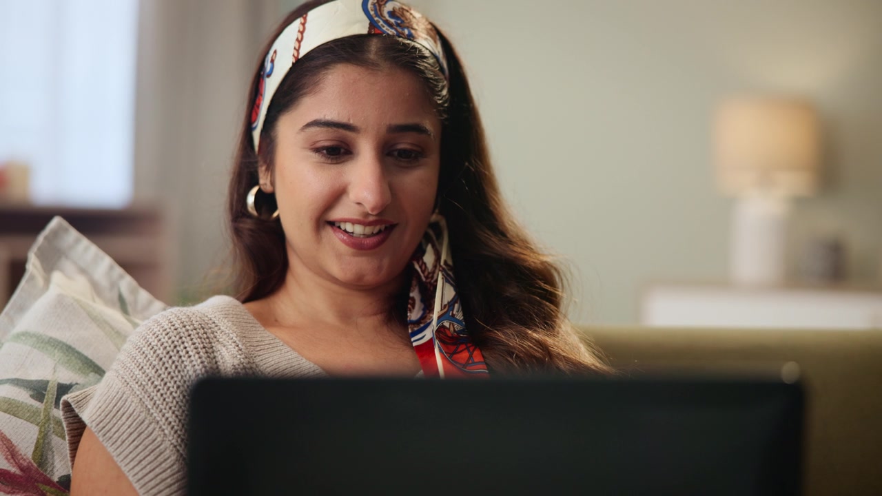 詳情圖-沙發(fā)，手表和印度女人在筆記本電腦上觀看電影流媒體服務(wù)，電影或故事有趣的戲劇。人們?cè)隗@訝，震驚和放松在家里的電腦為在線電視節(jié)目，連續(xù)劇和視頻