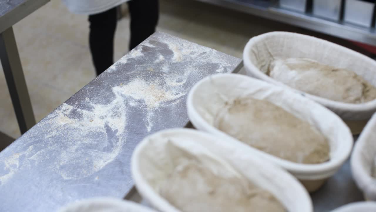 把生面团揉成几条面包，然后放在烤盘里。工艺面包店。做面包