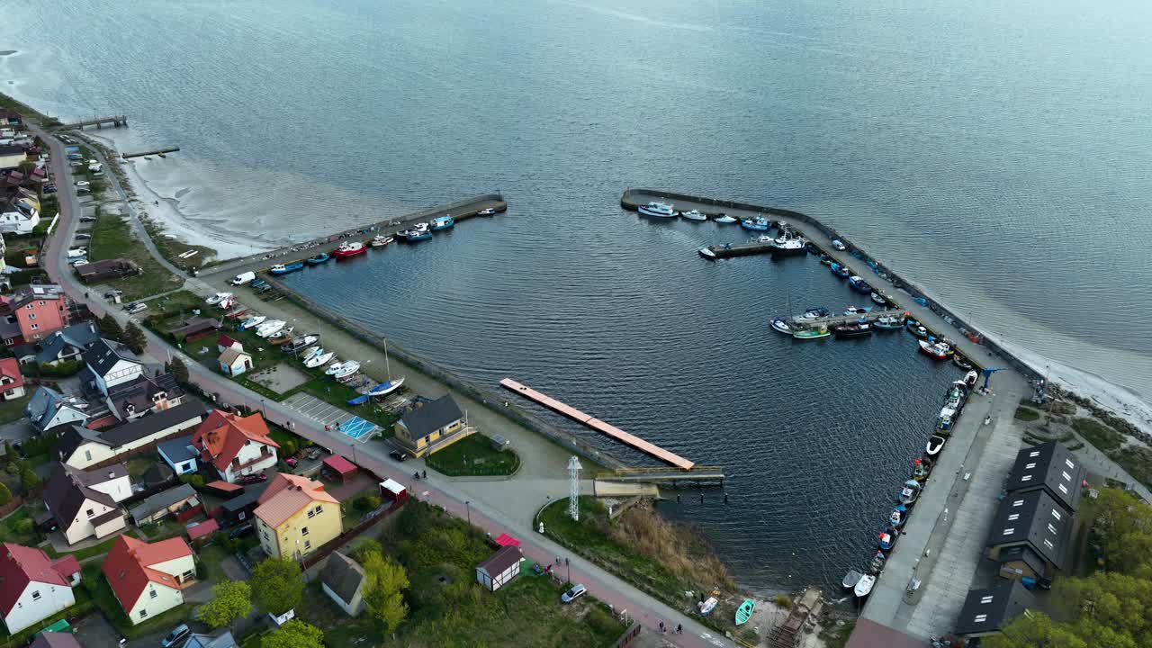 波罗的海沿岸Kuźnica港口的鸟瞰图，以码头，系泊船和周围的住宅区为特色，捕捉古朴而充满活力的海洋生活。