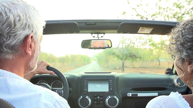成熟的夫妇在乡村道路上开敞篷车