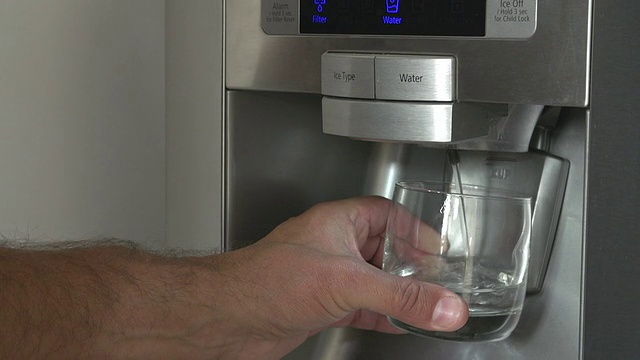 男人从冰箱里拿一杯冰水的特写