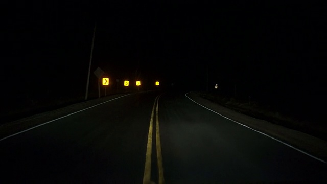 在漆黑的夜里行驶着弯弯曲曲的乡村公路