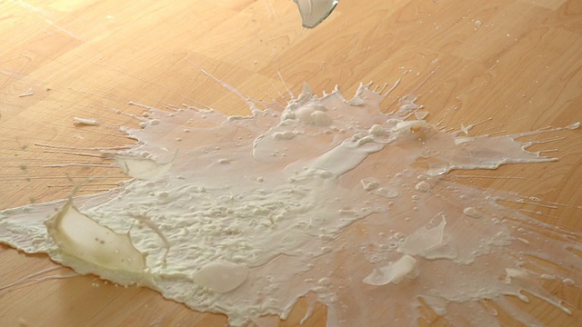 一杯牛奶掉在地上摔碎，慢镜头