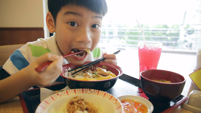 快乐的亚洲男孩吃日本午餐套装