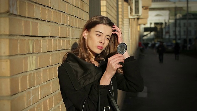 詳情圖-一個漂亮的年輕女子在街上照鏡子