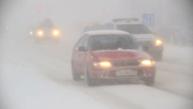 在冰岛的雷克雅未克，在暴风雪中车灯闪烁，能见度为零