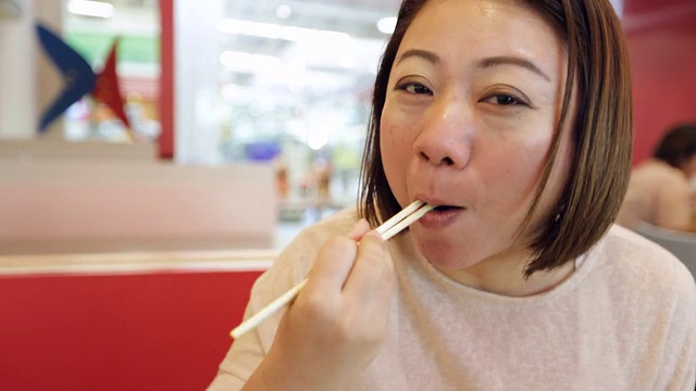 快乐的亚洲女人吃寿司在一个餐厅微笑的脸