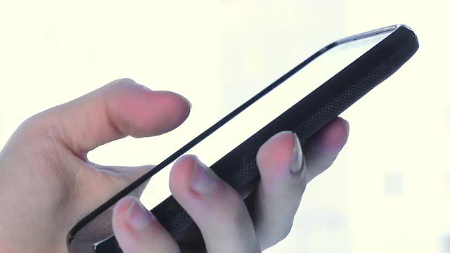 男人用左手在触控手机上输入短信，特写