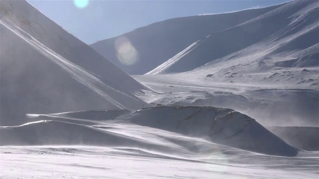 一个孤独的旅行者正穿过暴风雪，背景是雪山。