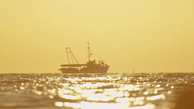 慢镜头:日落时分，渔船在海面上航行