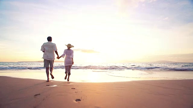 详情图-日落漫步海滩。老夫妇手牵着手，奔向夕阳，让他们的脚湿了