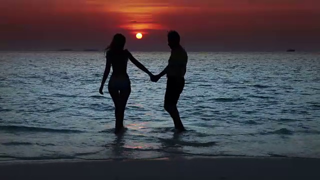那个男人和女人的剪影，在夕阳下去海边，在海浪中接吻