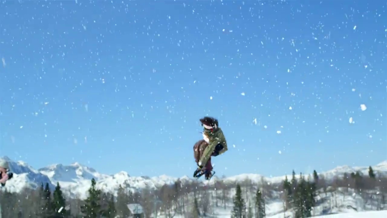 慢镜头特写:自由式滑雪者跳跃大kicker和飞越在雪山的太阳