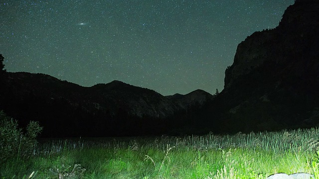 星星在夜空越过高山草地到日出