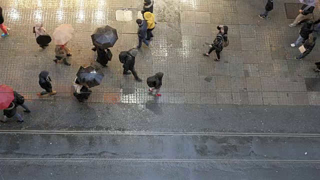 土耳其伊斯坦布尔，Beyoglu，一群人撑着雨伞在istikal街上行走。