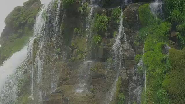 4K分辨率的山脉中间的瀑布和树木和岩石