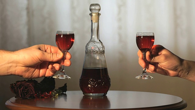 两只手碰杯，杯中倒入红色的酒