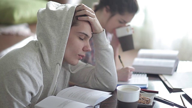 疲倦的穿着帽衫的男学生睡着了。