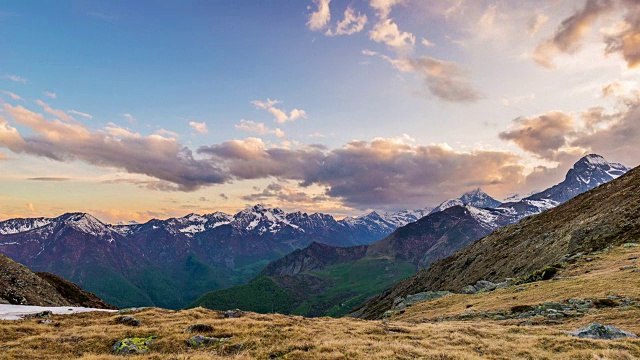 在日落时，雪山山脊和移动云的山峰的延时视图。阿尔卑斯山，都灵省，意大利。