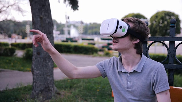 年轻人戴着3D VR头戴显示器在公园里观看360度电影，玩VR游戏