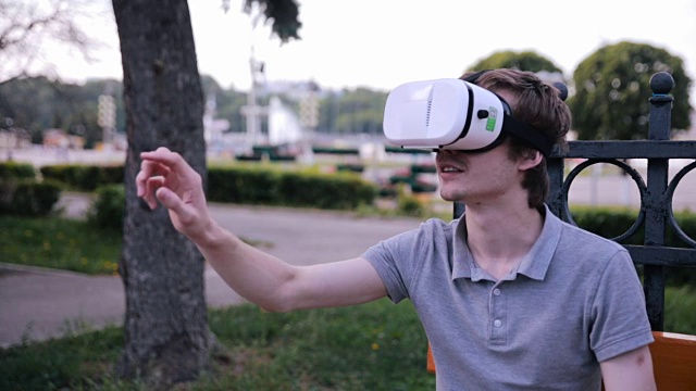 详情图-年轻人戴着3D,VR头戴显示器在公园里观看360度电影,玩VR游戏