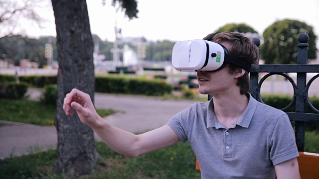 详情图-年轻人戴着3D,VR头戴显示器在公园里观看360度电影,玩VR游戏