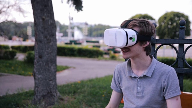 详情图-年轻人戴着3D,VR头戴显示器在公园里观看360度电影,玩VR游戏