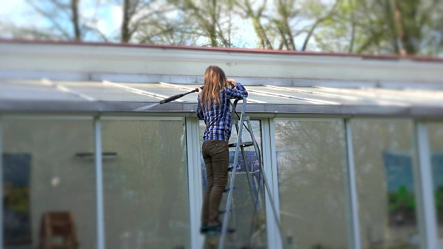 女人在用高压工具清洁玻璃屋顶。