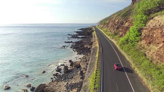 航拍:红色敞篷车沿着风景如画的海岸公路行驶