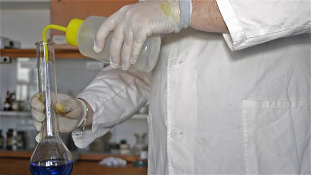 详情图-实验室技术人员用手手套稀释蓝色液体