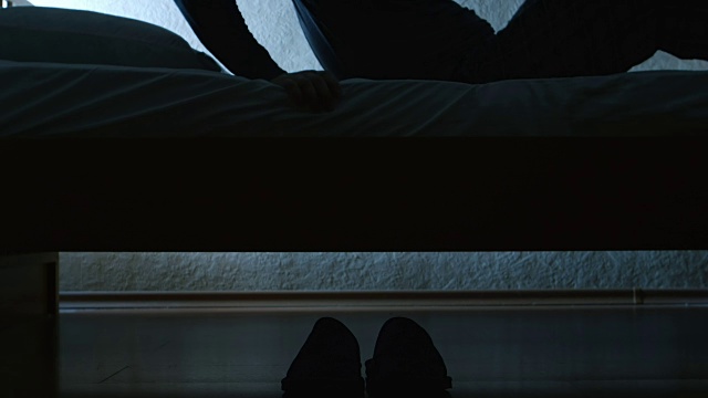 剪影:男人晚上从床上起来，穿着拖鞋走了