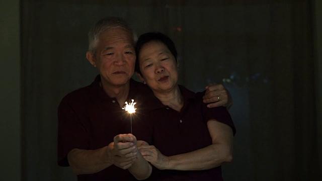 亚洲老夫妇玩烟花，烟花，爆竹在晚上。庆祝生活的概念