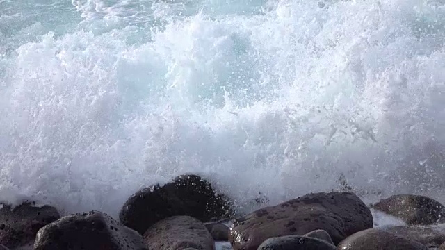 慢镜头特写:海浪破碎并溅入火山岩