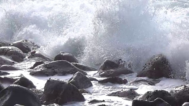 慢镜头特写:海浪撞击和溅溅圆形的火山岩