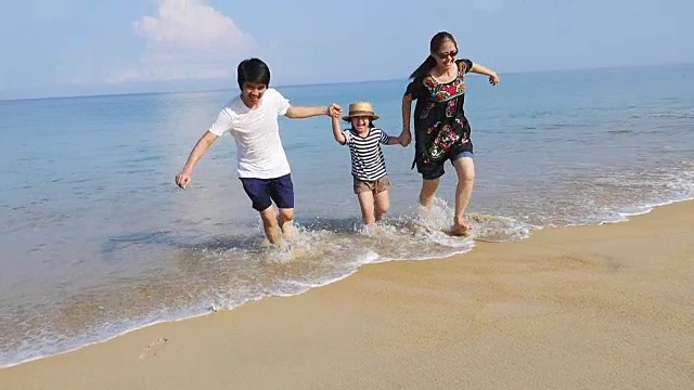 快乐亚洲一家一起在沙滩上跑步的慢镜头
