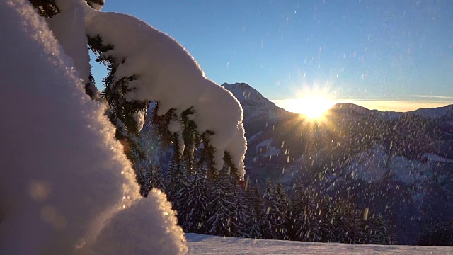 慢镜头:在神奇的日落时分，雪花飘落在洁白的雪毯上