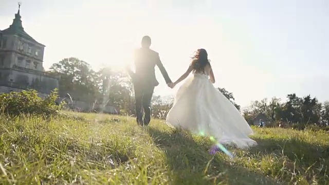 詳情圖-在日落城堡附近的草地上奔跑的新婚夫婦