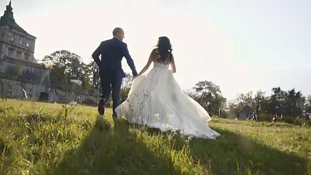 詳情圖-在日落城堡附近的草地上奔跑的新婚夫婦
