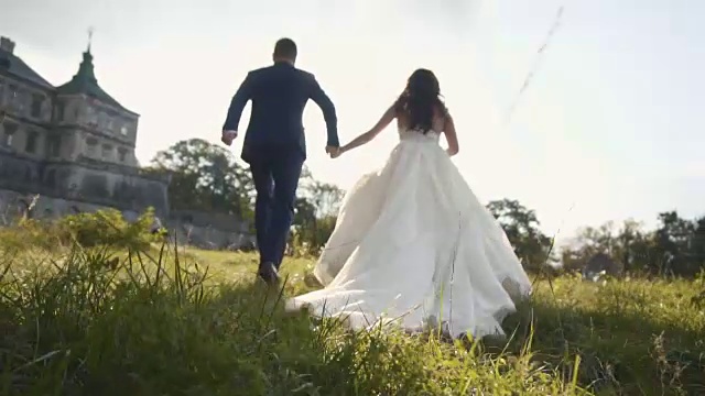 詳情圖-在日落城堡附近的草地上奔跑的新婚夫婦