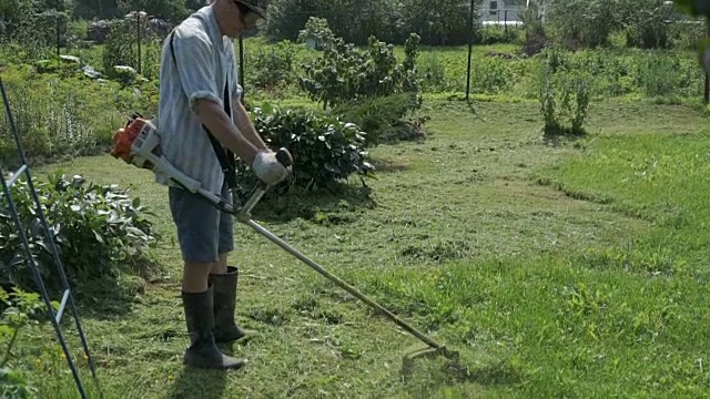 在花园里用割草机修剪草坪的人