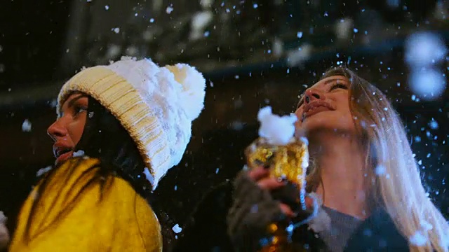 一群迷人的少女在户外庆祝。女性朋友们在玩，在雪地里跳舞。60帧/秒的慢动作