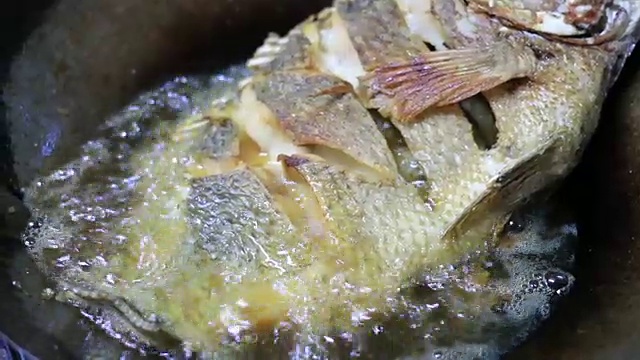 在厨房的临时火坑上炒罗非鱼(近景)