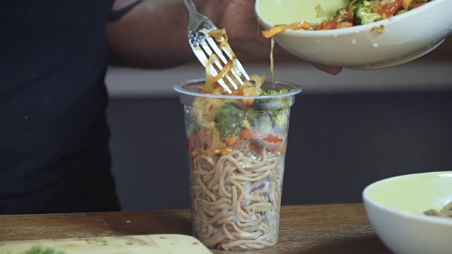 年轻人把米饭和蔬菜放在容器里，凑近了