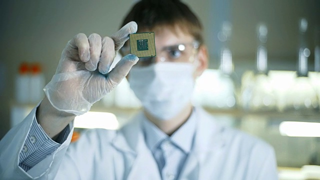 专业科学家拿着并观察微型芯片。